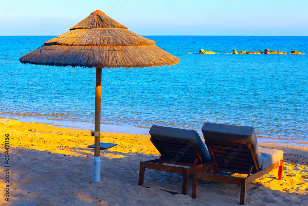 Chaise lounges and straw umbrella on tropical beach . Summer vacation concept 