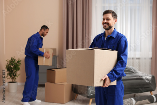 Male movers with cardboard boxes in new house