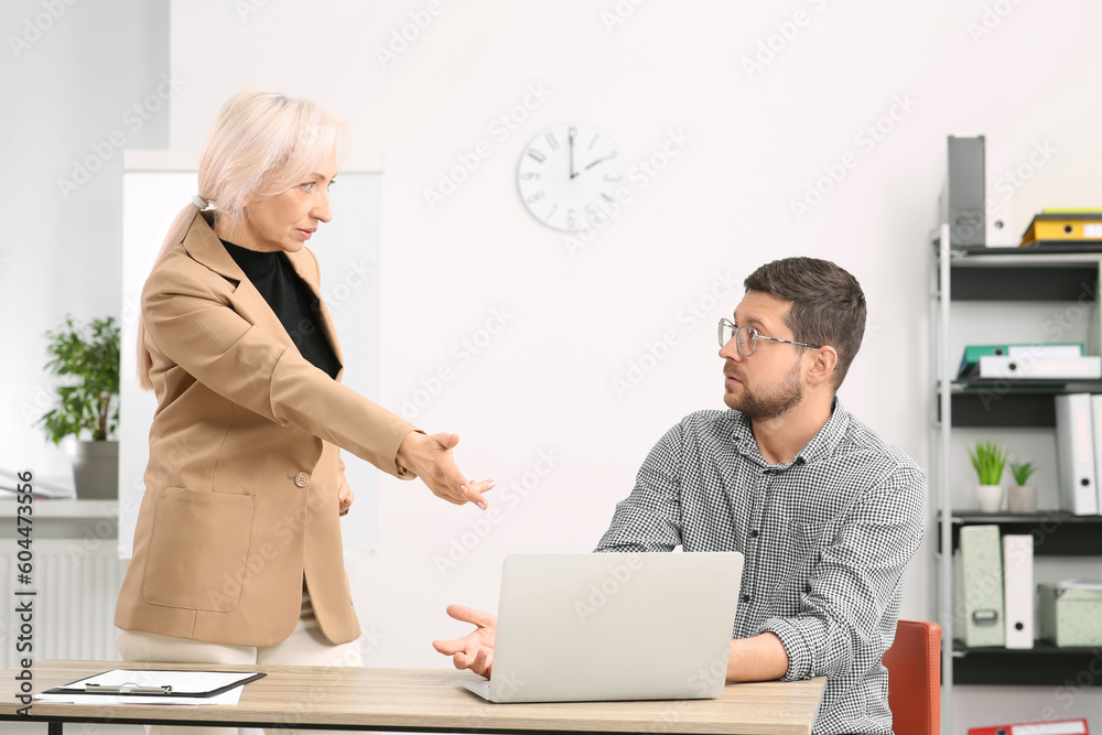 Emotional boss and confused employee discussing work issues in office
