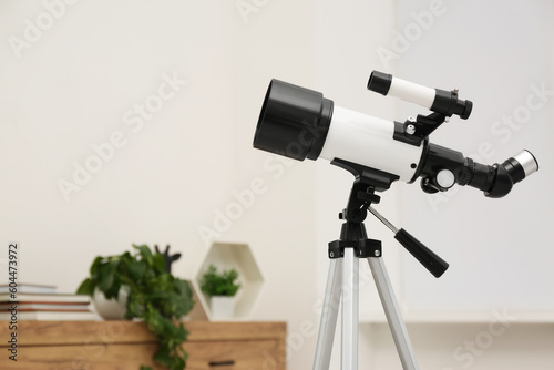 Tripod with modern telescope in stylish room, closeup. Space for text