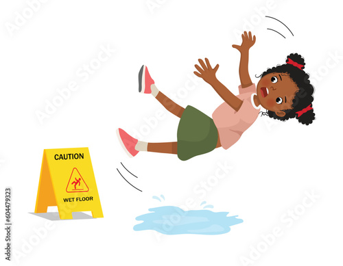 Cute little African girl having accident slipping on wet floor and falling down near yellow caution sign