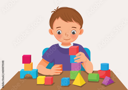 Cute little boy playing colorful wooden brick block toys at the table photo