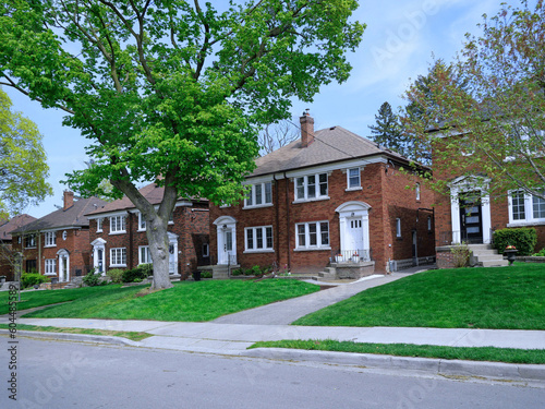 Suburban street with mature trees and large two story semi-detached houses