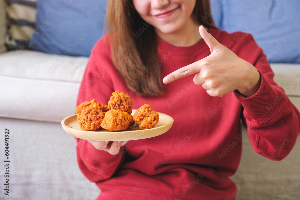 Closeup image of a woman holding and pointing finger at a plate of fried chicken Closeup image of a woman holding and pointing finger at a plate of fried chicken