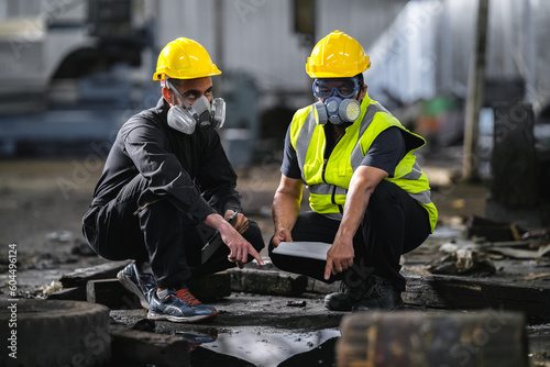 Fototapeta Two officers wearing gas masks inspected the area of a chemical leak in an industrial warehouse to assess the damage