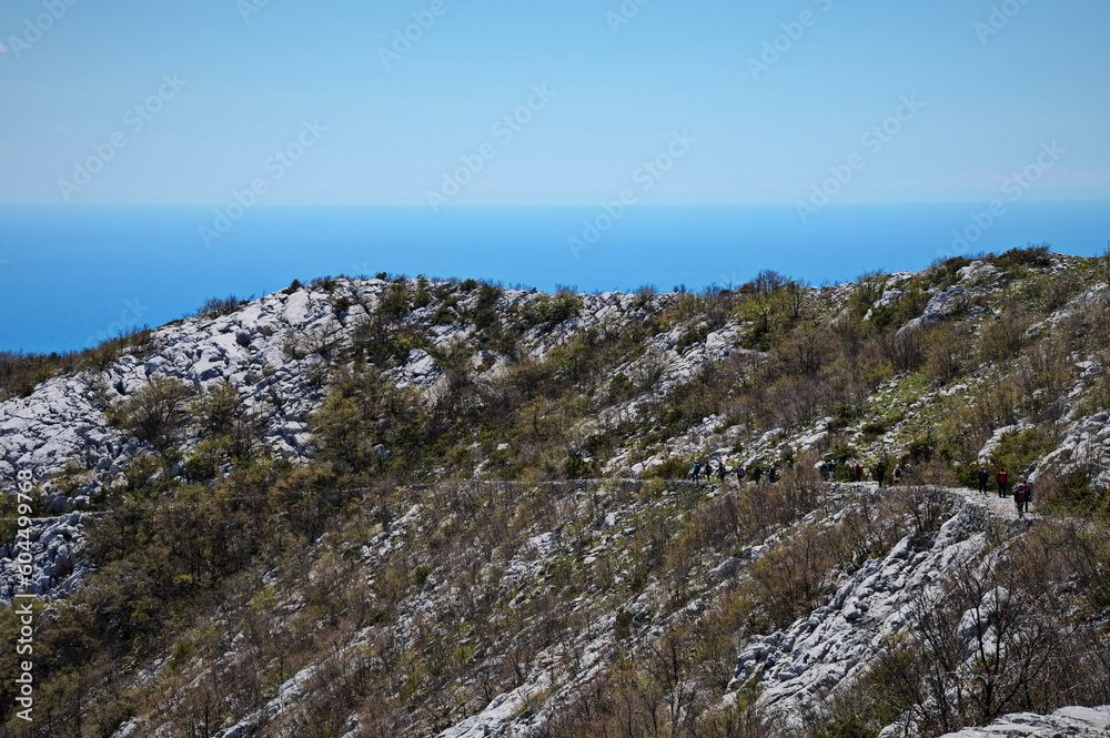 Group of unrecognizable people hiking in karst landscape of Croatian mountains