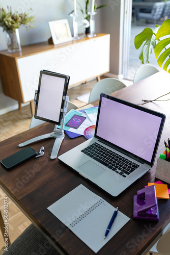 Notepad and smartphone with laptop and tablet with copy space on screens, on dining table at home