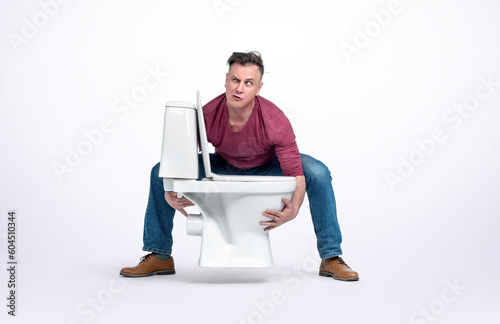 A man in casual clothes holds a toilet bowl in his hands, isolated on a light background