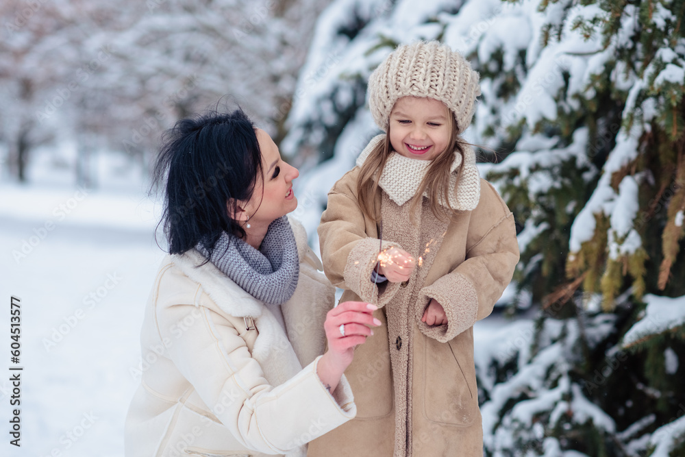Obraz premium little girl with mom joyfully in winter in frosty forest under snow. Family in the winter forest on a frosty day. mother hugging daughter