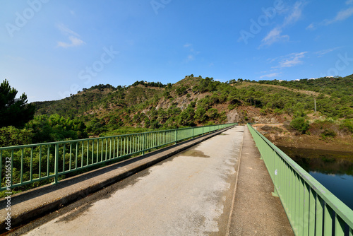 paisaje de montaña con lago y pasarela con barandilla de hierro verde en Marbella España
