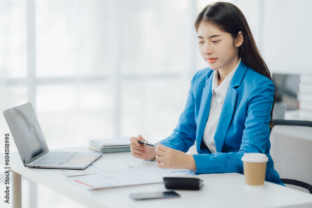 Asian Business woman using calculator and laptop for doing math finance on an office desk, tax, report, accounting, statistics, and analytical research concept Asian Business woman using calculator and laptop for doing math finance on an office desk, tax, report, accounting, statistics, and analytical research concept