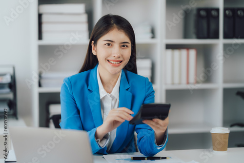 Asian Business woman using calculator and laptop for doing math finance on an office desk  tax  report  accounting  statistics  and analytical research concept