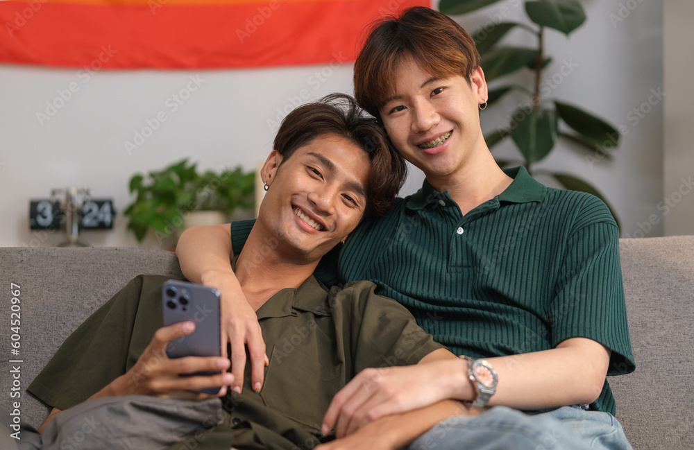 Happy homosexual couple relaxing on couch at home, spending time together at home. LGBT, love, relationship and equality concept.