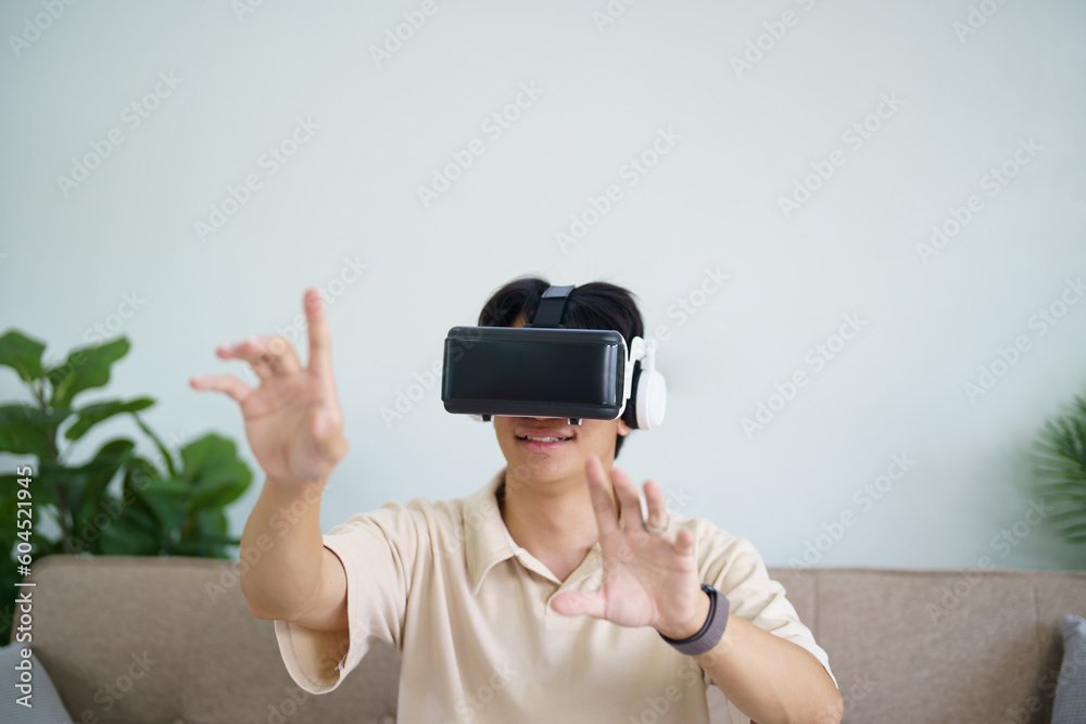 Young Asian man gamer wearing virtual reality touching air during the VR experience Future home technology player hobby playful enjoyment concept. Young Asian man gamer wearing virtual reality touching air during the VR experience Future home technology player hobby playful enjoyment concept.