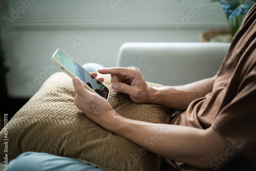 Relaxed young asian man using smart phone  spending time checking news social media
