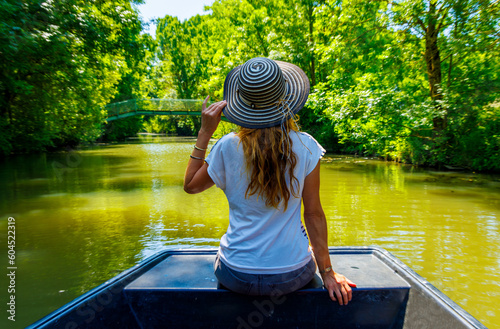 Rear view of woman with hat on boat looking at river- Marais poitevin in France