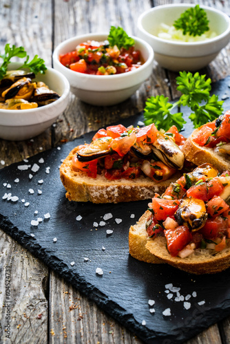 Tasty sandwiches - toasted bread with tomatoes and clams on wooden table
