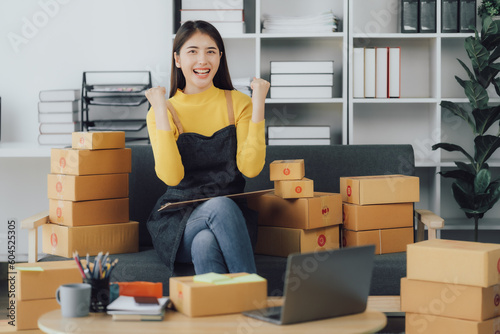 tarting Small business entrepreneur SME freelance,Portrait young woman working at home office, BOX,smartphone,laptop, online, marketing, packaging, delivery, SME, e-commerce concept © Kritdanai