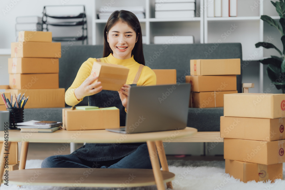 tarting Small business entrepreneur SME freelance,Portrait young woman working at home office, BOX,smartphone,laptop, online, marketing, packaging, delivery, SME, e-commerce concept