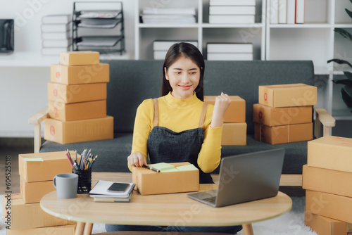 tarting Small business entrepreneur SME freelance,Portrait young woman working at home office, BOX,smartphone,laptop, online, marketing, packaging, delivery, SME, e-commerce concept