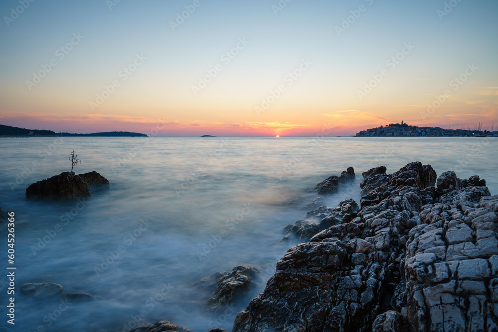 Sunset at the sea in Primošten, Croatia, with rocks in the foreground