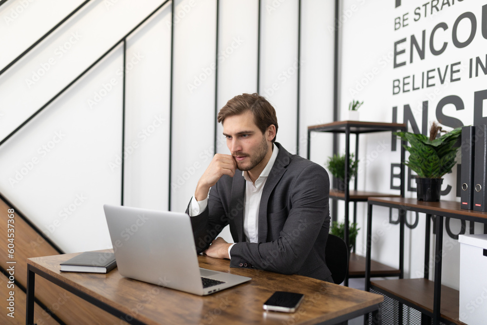 office worker man in a jacket sitting at work at a laptop office worker man in a jacket sitting at work at a laptop