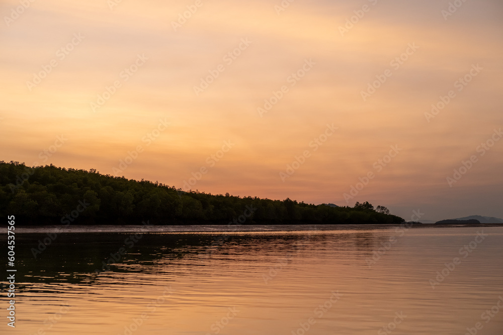 Sunrise view with colorful sky and the sea, with silhouette of the forest on the background