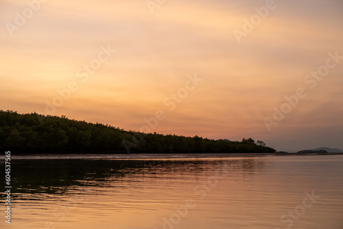 Sunrise view with colorful sky and the sea, with silhouette of the forest on the background