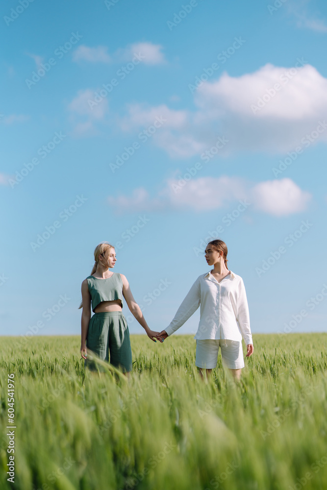 Two fashion woman in the green field. Fashion concept. Beautiful figures. Summer concept. Two fashion woman in the green field. Fashion concept. Beautiful figures. Summer concept.