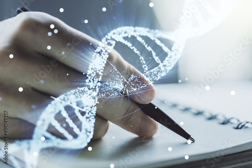 Double exposure of creative DNA hologram and man hand writing in notebook on background. Bio Engineering and DNA Research concept