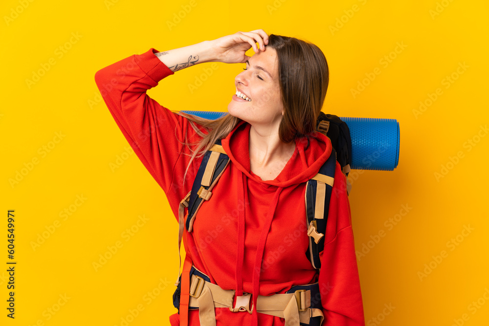 Slovak mountaineer woman with a big backpack isolated on yellow background smiling a lot Slovak mountaineer woman with a big backpack isolated on yellow background smiling a lot