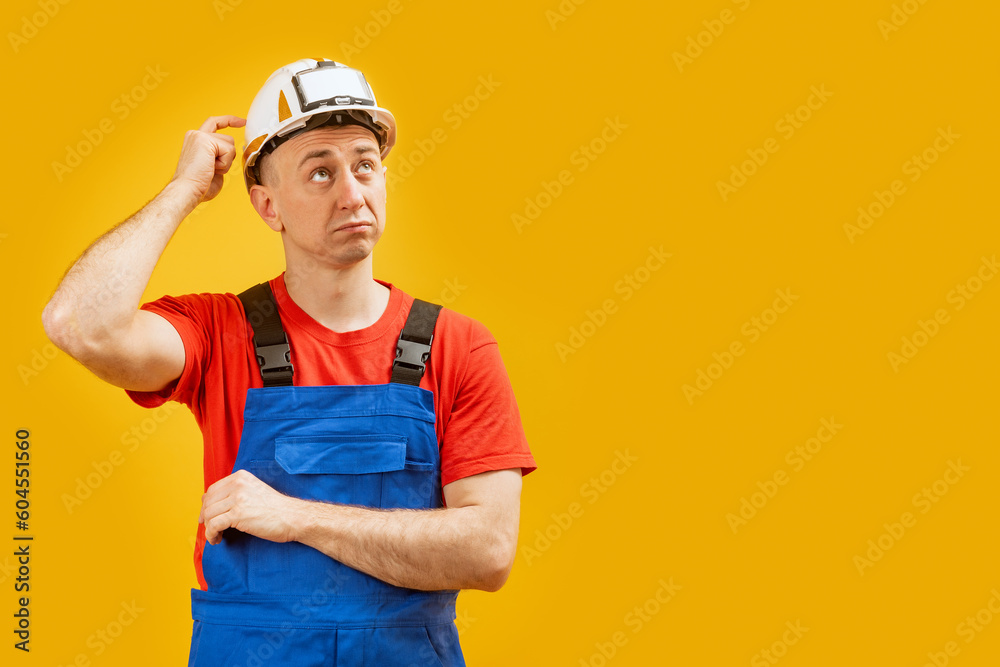 Portrait of Disapointment man engineer thinking and looking up. Builder or worker wears helmet and uniform. Copy space, mockup Portrait of Disapointment man engineer thinking and looking up. Builder or worker wears helmet and uniform. Copy space, mockup
