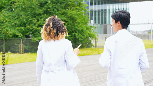 A multinational group wearing a white coat and walking through a outdoor facility