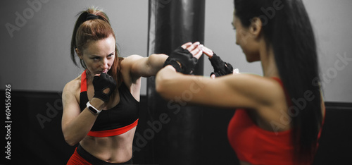 Woman exercising with trainer at boxing and self defense lesson. MMA training