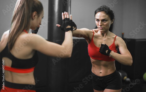 Woman exercising with trainer at boxing and self defense lesson. MMA training