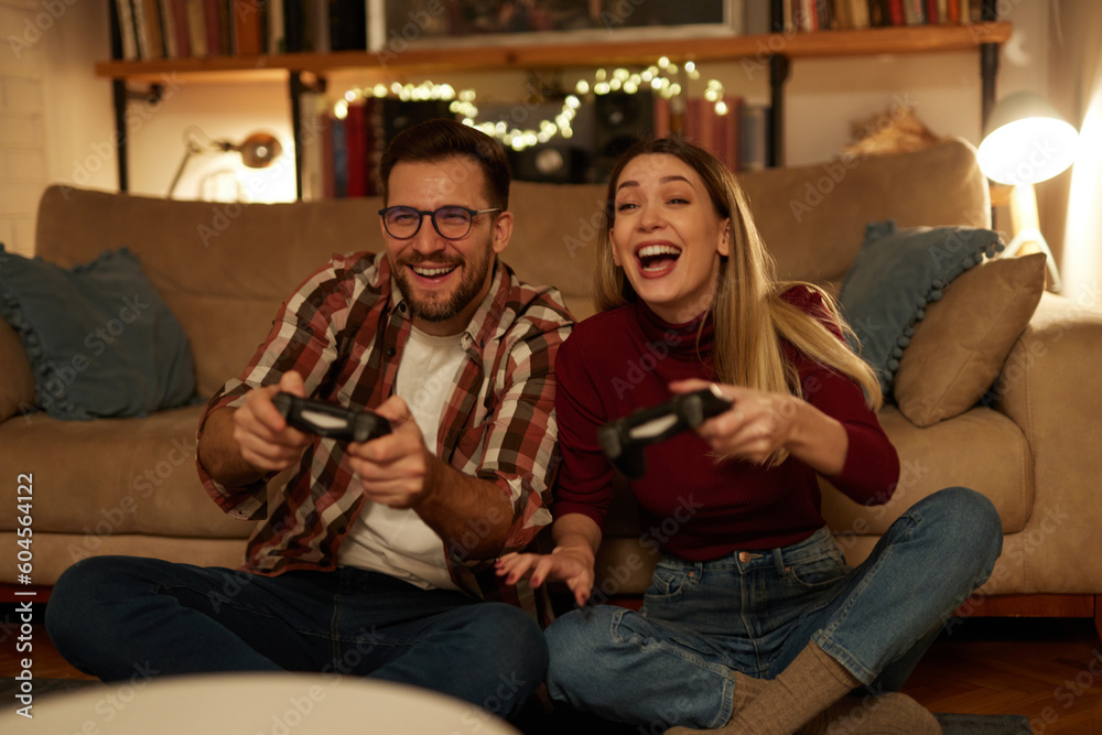 Obraz premium Young couple having fun at home playing video games