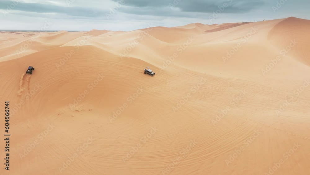 Aerial view of ATV buggy sport car riding fast by sand dunes. Group of four wheel drive vehicles competing on dunes. Extreme sport outdoor hobby on weekend day. Sport recreation concept for men 4K