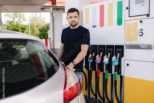 Handsome bearded man refueling car at self service gas station. Petrol concept photo