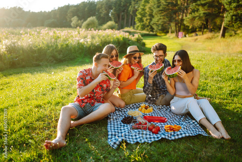 Group of friends have fun together and eating watermelon in hot summer day. People, lifestyle, travel, nature and vacations concept. 
