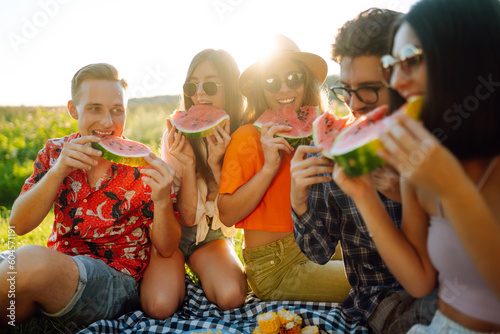Group of friends have fun together and eating watermelon in hot summer day. People, lifestyle, travel, nature and vacations concept. 