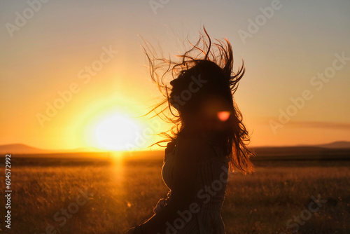 silhouette of a girl with her hair blowing in the wind at sunset