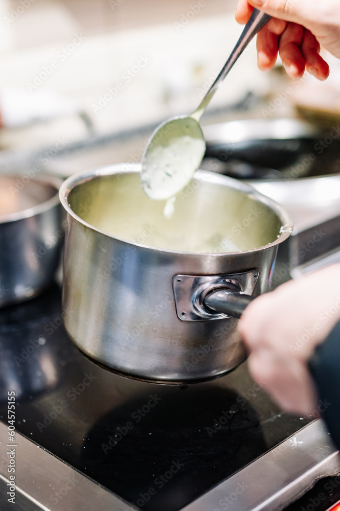 Chef hands cooking cheese sauce in the restaurant kitchen Chef hands cooking cheese sauce in the restaurant kitchen
