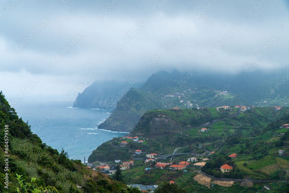 Amazing view of the village Porto da Cruz in Madeira island, Portugal. Small city in the hills by the coast of the Atlantic ocean. Dominant rock by the ocean. Portuguese tourist destination.