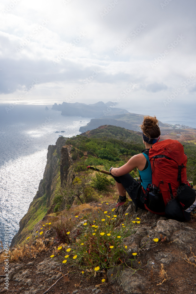 woman backpacker sit on mountain peak cliff rock enjoy the view, madeira