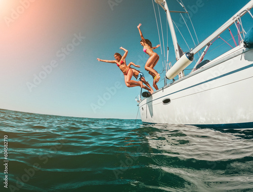 Photographie Happy friends diving from sailing boat into the sea - Soft focus on left girl fa