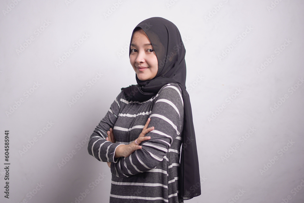 Cheerful beautiful Asian muslim woman in brown sweater crossing hands and smiling at camera isolated over white background