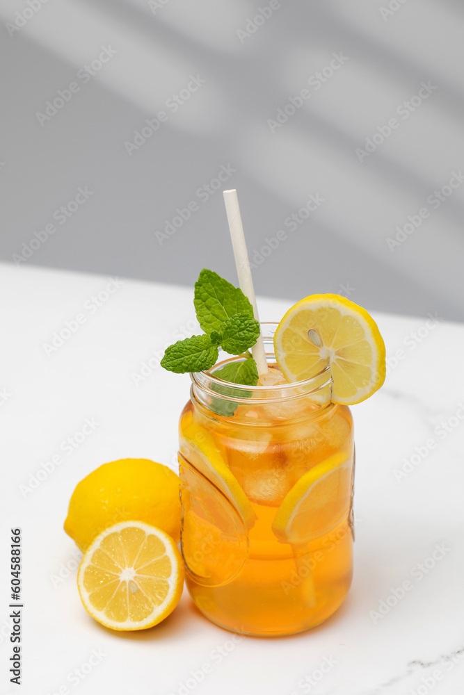 Fototapeta premium A glass of cold tea, ice cubes, lemon slices and a sprig of mint. Cooling summer drinks.