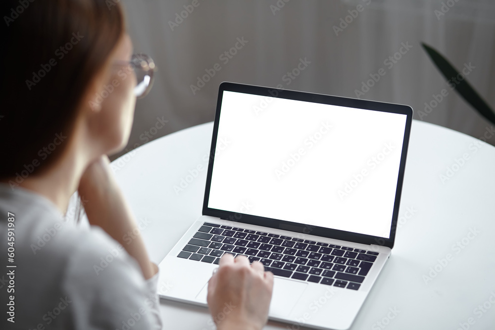 Mockup white screen laptop woman using computer while sitting at table at home, back view Mockup white screen laptop woman using computer while sitting at table at home, back view
