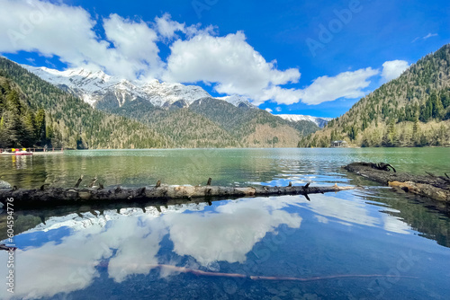 View on Lake Ritsa in Abkhazia, Georgia. Lake Ritsa is a lake in the Caucasus Mountains. Snow lies on the top of the mountains. The sky with clouds is reflected on the surface of the water