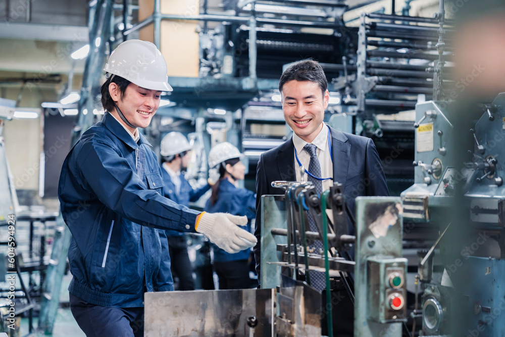機械の前で話をする営業マンと労働者 機械の前で話をする営業マンと労働者